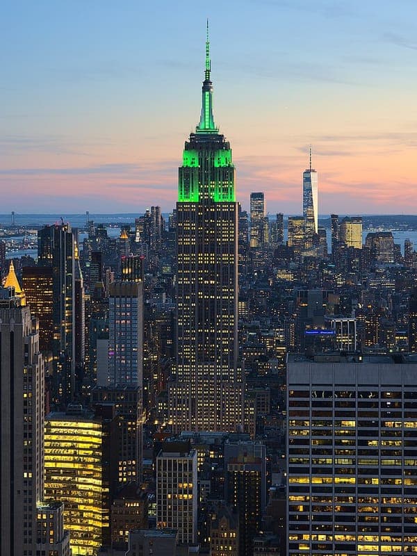 The Empire State Building lit green above the Manhattan skyline at dusk